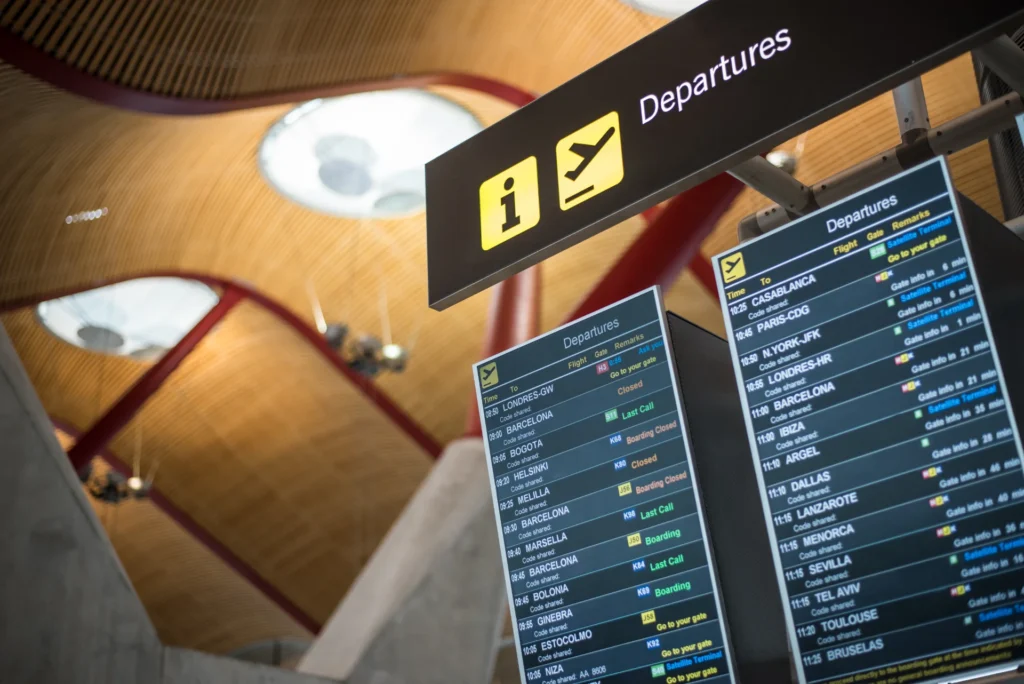 Panneaux d'affichage des départs dans un aéroport. Les panneaux indiquent les destinations, les heures de vol et les informations sur les portes.